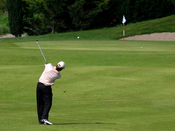 A golfer hitting their approach shot into a green on a golf course